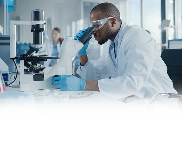 Male researcher looking into microscope 