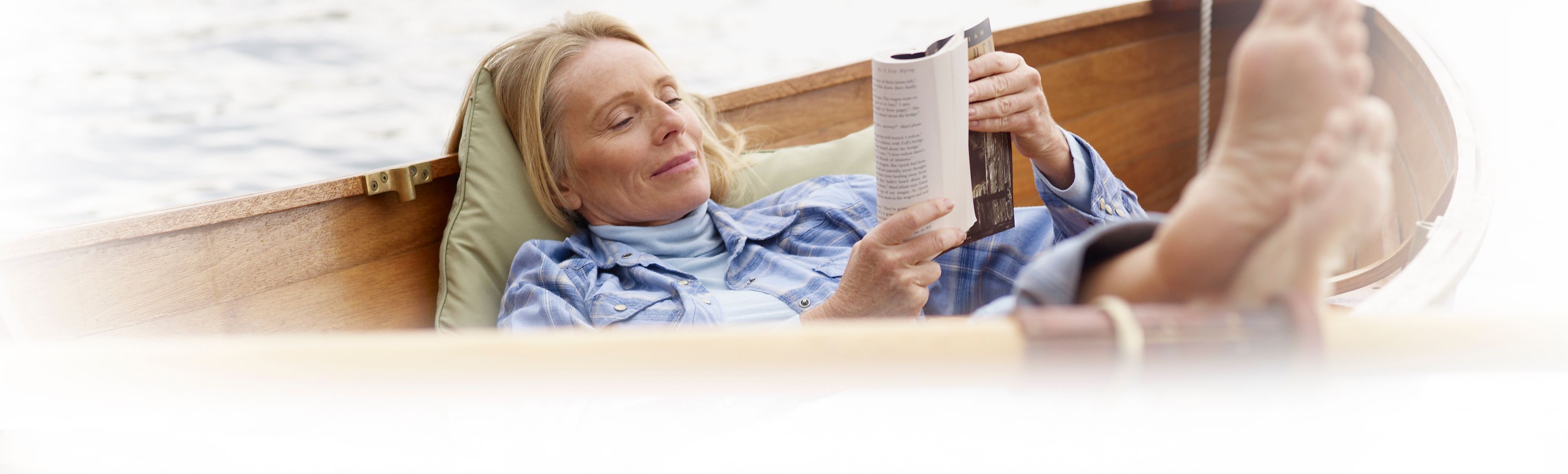 A woman relaxes in a boat while reading a book